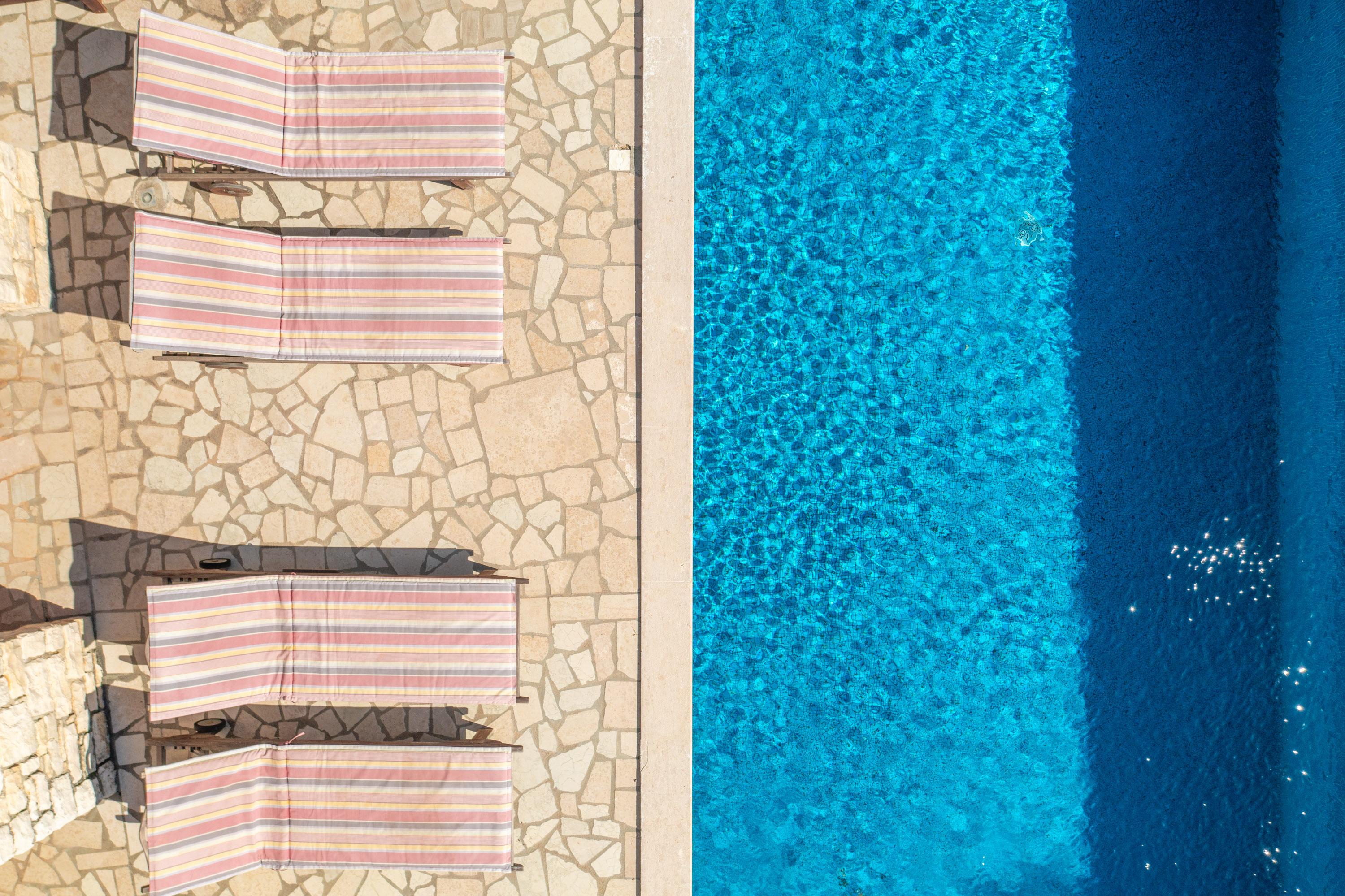 Sunbeds and pool closeup photo taken from air directly above
